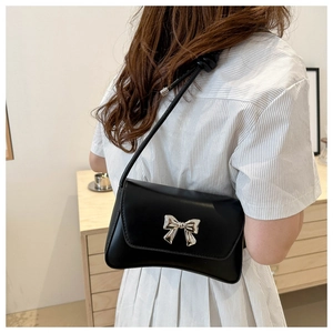 Sac sous le bras chic en cuir noir avec un fermoir nœud argenté porté par un mannequin