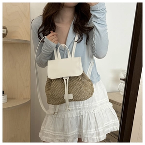 Detail of hand-woven straw backpack with white faux leather straps and drawstring closure