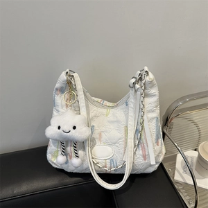 Detail of white canvas hobo bag with colorful embroidery and plush cloud charm