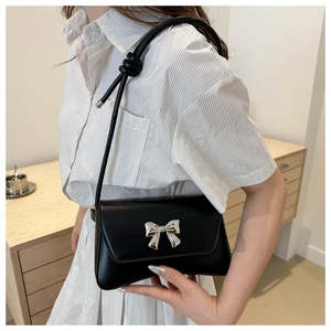 Détail du sac bandoulière en cuir noir avec nœud métallique argenté et bandoulière nouée