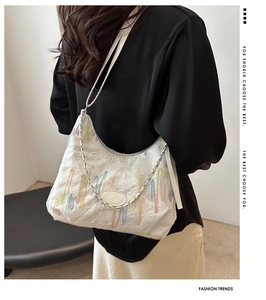 Detail of white tote bag with colorful wavy embroidery and silver chain strap