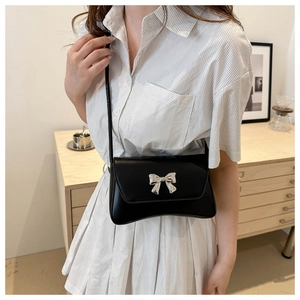 Gros plan d'un sac à bandoulière en similicuir noir avec un nœud métallique argenté chic