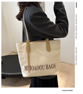 Détail du sac cabas en toile avec lettres imprimées et anses en similicuir marron