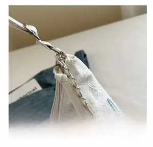 Close-up of minimalist canvas tote with pink blue embroidery and chain leather strap