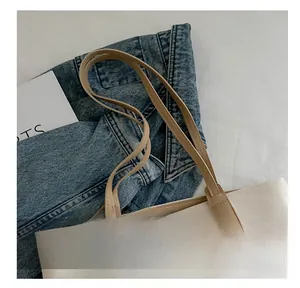Detail of leather handles and canvas stitching on a large commuter tote bag
