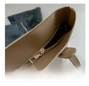 Macro shot of smooth golden metal zipper and brown leather trim on white canvas tote