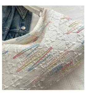 Detail of white quilted tote bag featuring colorful embroidery and 3D floral textures
