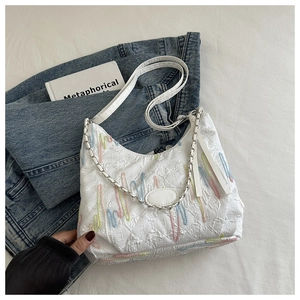 Detail of white quilted canvas hobo bag with colorful wave embroidery and silver chain