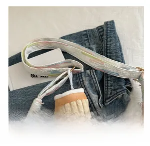 Detail of embroidered canvas bag strap and cute plush cupcake pendant on denim
