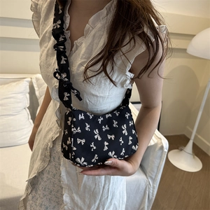 Black canvas underarm bag with white bow prints and scrunched shoulder strap for women