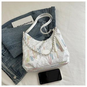 Detailed close-up of white canvas tote bag featuring colorful wavy embroidery and silver chain