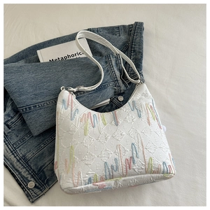 Detail of white canvas tote bag with 3D letter embossing and colorful wavy embroidery
