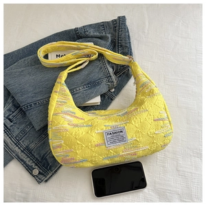 Detail of yellow nylon hobo bag featuring colorful dashed embroidery and fashion patch