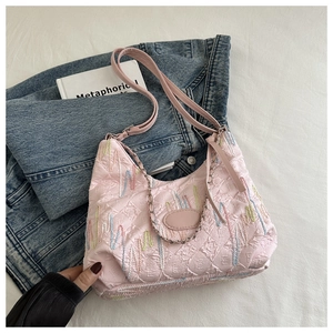 Detail of pink quilted tote bag featuring vibrant wavy embroidery and dual straps