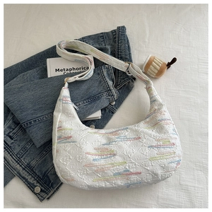 Detailed top view of a white nylon crescent bag with colorful floral embroidery