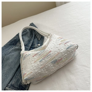 Close-up of quilted white nylon bag with colorful embroidery and monogram detail