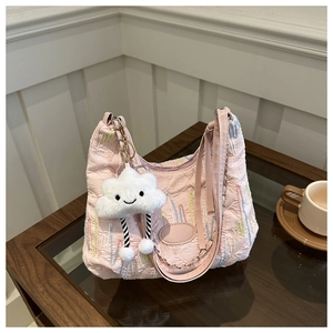 Detail of light pink quilted hobo bag with colorful embroidery and plush cloud charm