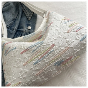 Detail of white quilted nylon bag featuring colorful wavy embroidery and wide soft strap