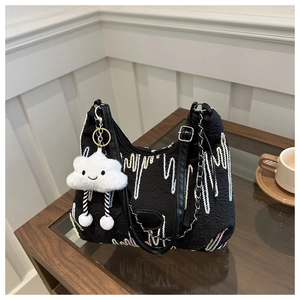 Detail of black canvas tote with rainbow wave embroidery and a white cloud plush charm