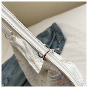 Detailed close-up of white nylon bag featuring colorful embroidery and silver hardware