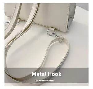 Macro-opname van zilveren metalen haak en strakke stiksels op beige kunstlederen tas