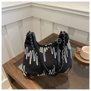 Detail of black tote with wave stitching and chain strap on a wooden table cafe setting