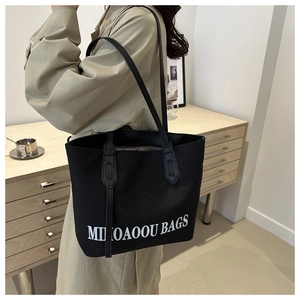 Detail of the black large capacity tote bag featuring white MIKOAOUU BAGS print