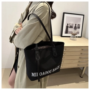 Close-up of black tote bag interior lining and leather handle in a minimalist room