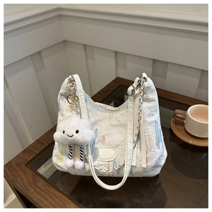 Close-up of white canvas tote bag with colorful embroidery and plush cloud charm