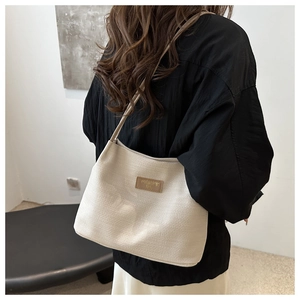 Detailed knit texture of beige hobo bag featuring a decorative brown leather patch