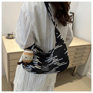 Detailed shot of black crescent bag with colorful wavy embroidery and plush coffee cup charm