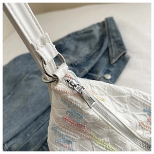 Detail view of white fabric bag with colorful wavy embroidery and silver zipper