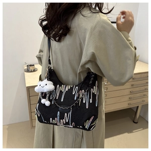 Detail of black tote bag with colorful embroidery and white cloud plush charm