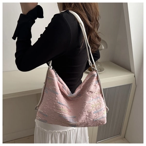 Detail of pink pleated tote bag featuring colorful wavy embroidery and adjustable strap