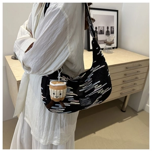 Detail of black crescent bag with colorful wave embroidery and plush cup charm