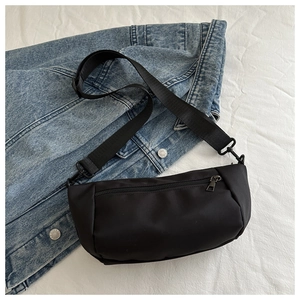 Detail of minimalist black nylon crossbody bag with metal zipper and adjustable strap