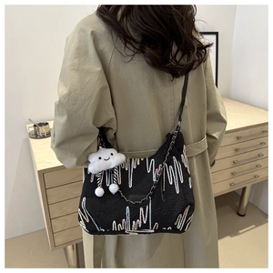 Detail of black tote bag featuring colorful embroidery and cute cloud charm on shoulder