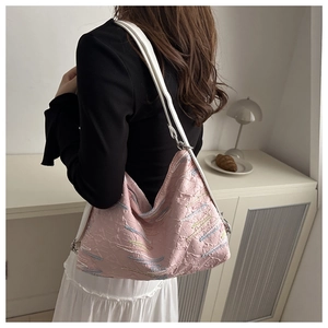 Detail of pink pleated nylon crossbody bag featuring colorful embroidery and white strap