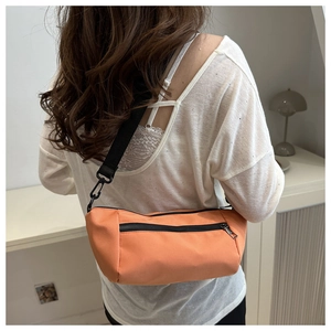 Rear view of model wearing a bright orange nylon baguette bag with black zipper detail