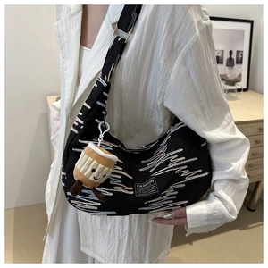 Close-up of black crossbody dumpling bag with wavy embroidery and cute coffee cup charm