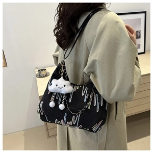 Close-up of black fabric tote bag featuring colorful embroidery and a plush cloud charm