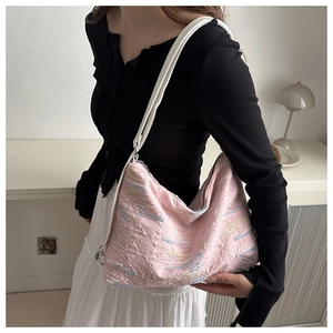 Detail of pink embroidered tote bag with textured fabric worn by model in home setting