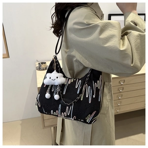 Detail of black canvas tote bag with wave embroidery, plush charm, and chain strap