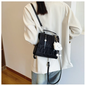 Close-up of black pleated texture backpack with cute white cloud plush pendant accessory
