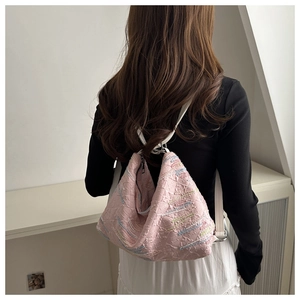 Detail view of pink quilted nylon backpack with colorful embroidery on a female model
