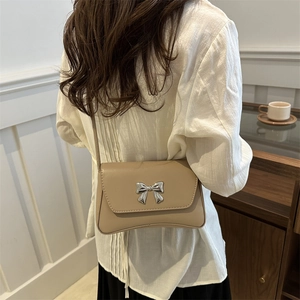 Sac à bandoulière beige minimaliste avec nœud argenté et base au design incurvé