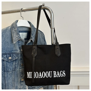 Détail du grand sac cabas en toile noire avec inscription MILIOAOOU BAGS et lanières