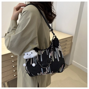 Detail of black canvas tote with colorful embroidery and a white cloud plush charm