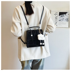 Detail of black crinkle texture mini backpack with cute white cloud plush pendant