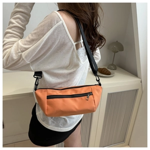 Detail of orange nylon crossbody bag with zipper pocket and adjustable black strap